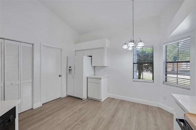 unfurnished dining area featuring an inviting chandelier, a high ceiling, light wood-style floors, and baseboards