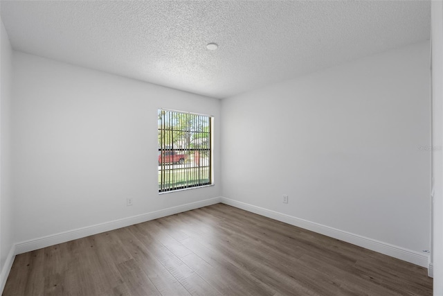 spare room with baseboards, a textured ceiling, and dark wood finished floors