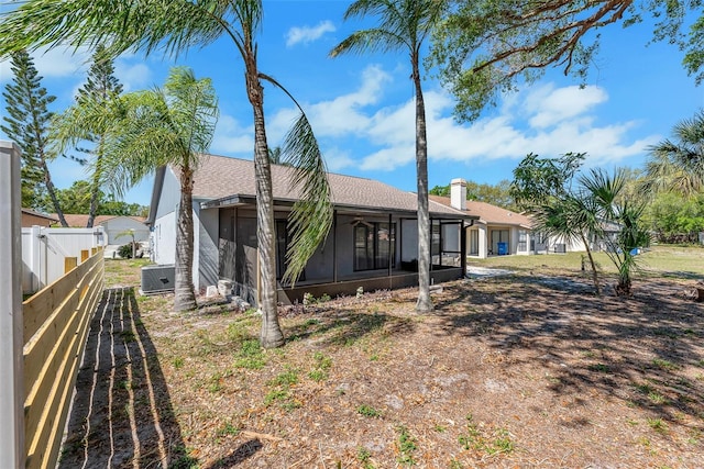 back of property with cooling unit, fence, and a sunroom