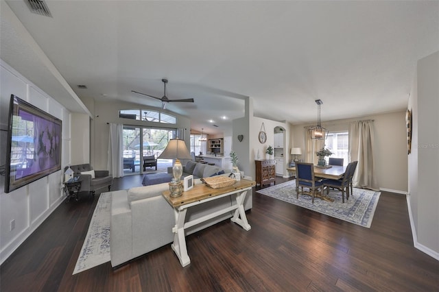 living area featuring visible vents, a ceiling fan, wood finished floors, baseboards, and lofted ceiling