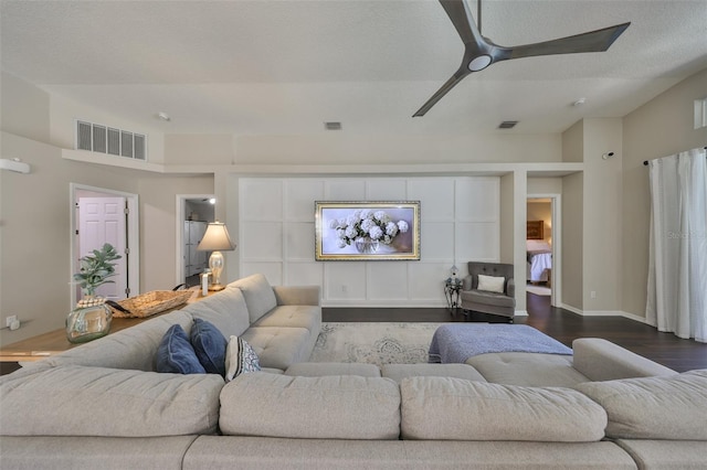 living room featuring visible vents, dark wood-style flooring, and ceiling fan