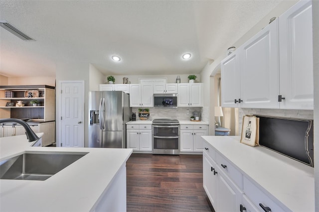 kitchen featuring visible vents, a sink, tasteful backsplash, appliances with stainless steel finishes, and dark wood-style flooring