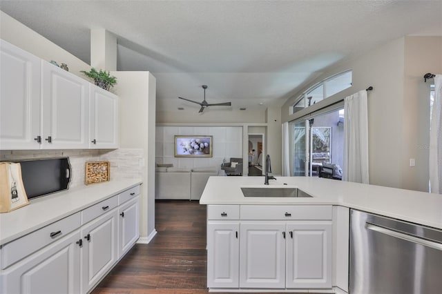 kitchen with a sink, dark wood finished floors, white cabinets, light countertops, and dishwasher