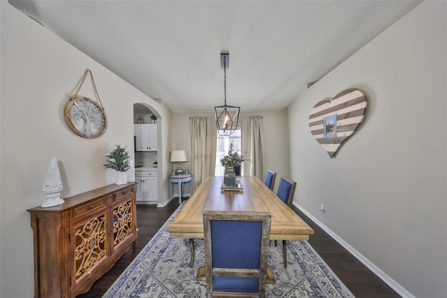 dining room featuring baseboards, dark wood-type flooring, and arched walkways