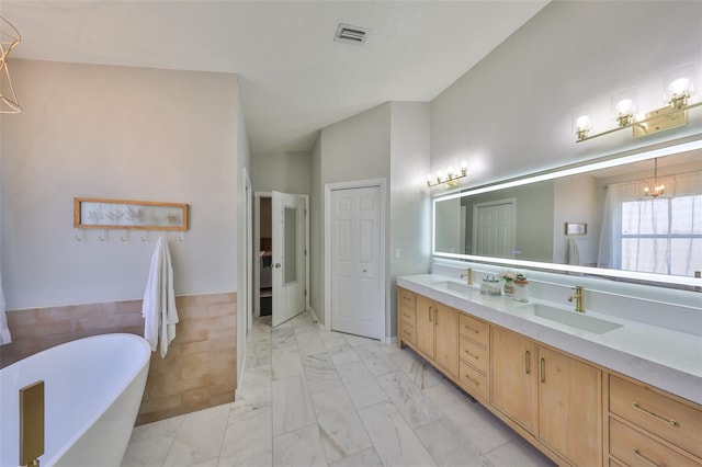 bathroom with double vanity, a soaking tub, marble finish floor, and a sink