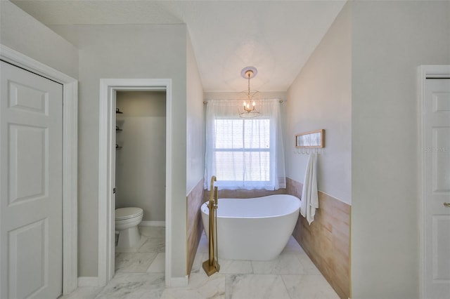 bathroom with a notable chandelier, a soaking tub, marble finish floor, and toilet