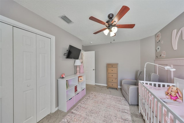 bedroom featuring visible vents, ceiling fan, a closet, a textured ceiling, and light carpet