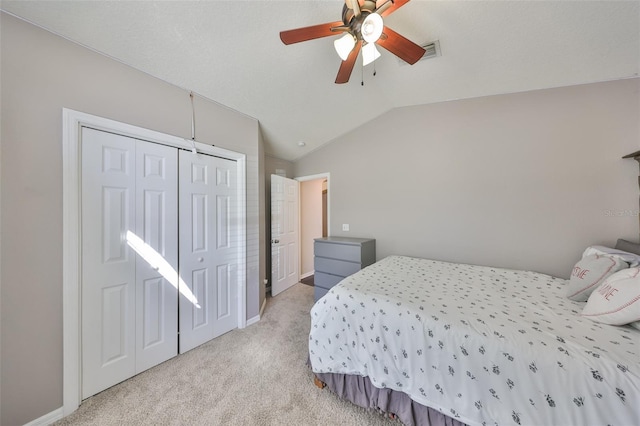 bedroom with visible vents, ceiling fan, vaulted ceiling, a closet, and light colored carpet