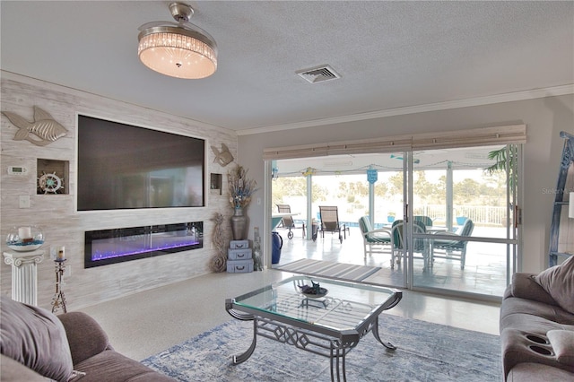 living room featuring visible vents, ornamental molding, a textured ceiling, and a glass covered fireplace