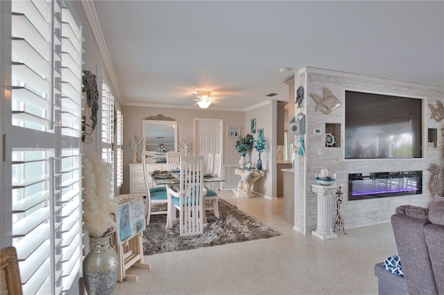 interior space featuring ceiling fan, speckled floor, a glass covered fireplace, and crown molding