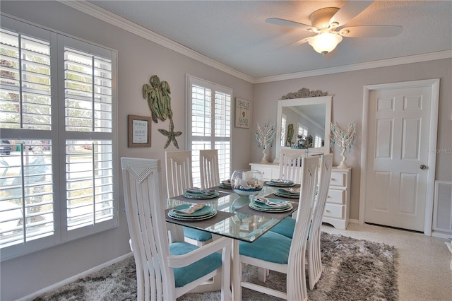 carpeted dining space with visible vents, baseboards, crown molding, and ceiling fan