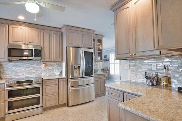 kitchen with glass insert cabinets, light stone countertops, tasteful backsplash, and stainless steel appliances