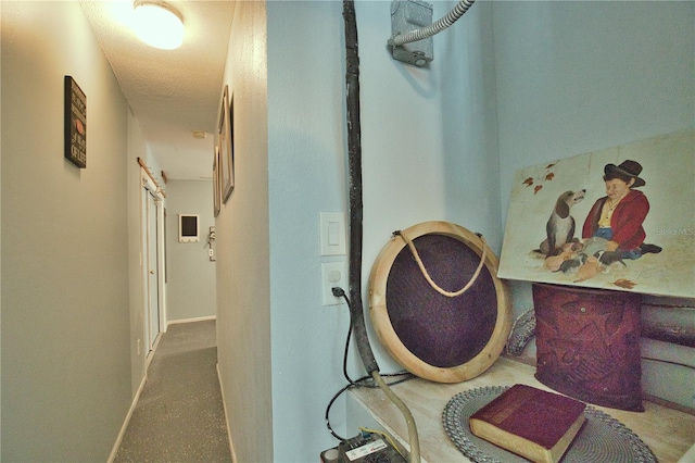 hallway with baseboards and a textured ceiling