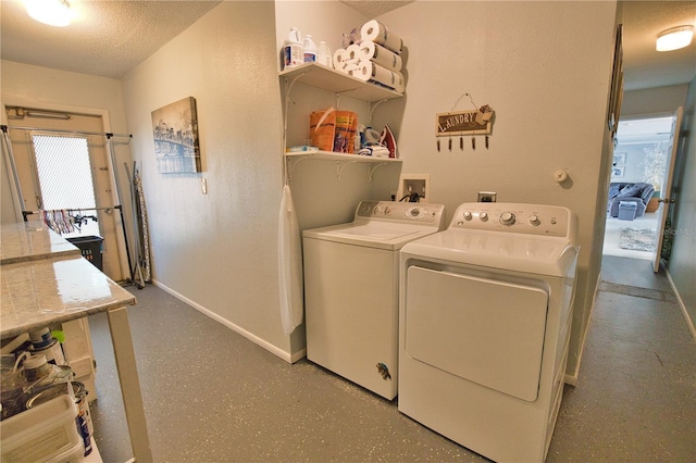 laundry room with a textured ceiling, baseboards, and washing machine and clothes dryer