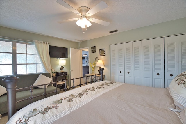 bedroom with visible vents, a textured ceiling, ceiling fan, and carpet floors