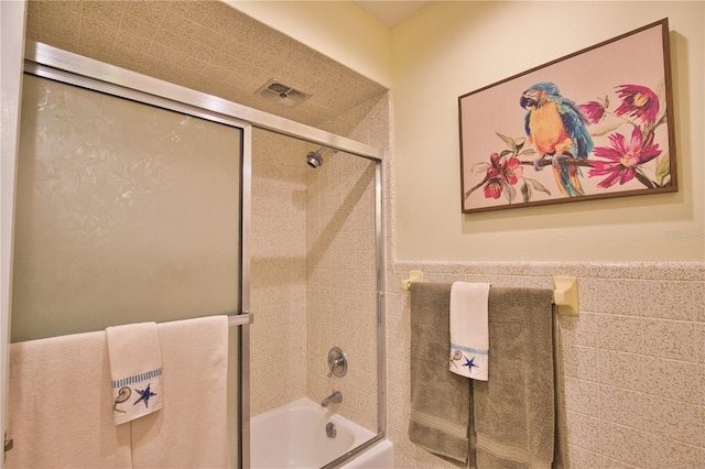 full bath featuring visible vents, shower / bath combination with glass door, and wainscoting