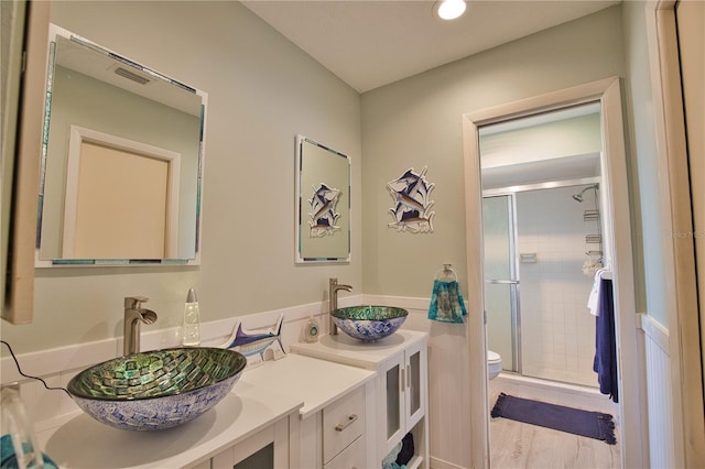 full bath featuring a shower stall, toilet, double vanity, and a sink