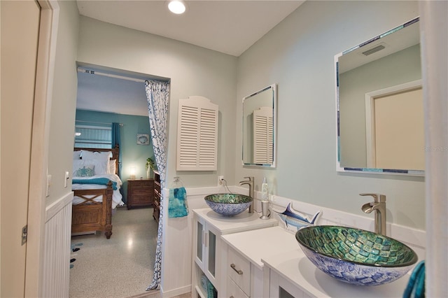 ensuite bathroom featuring double vanity, connected bathroom, visible vents, and a sink