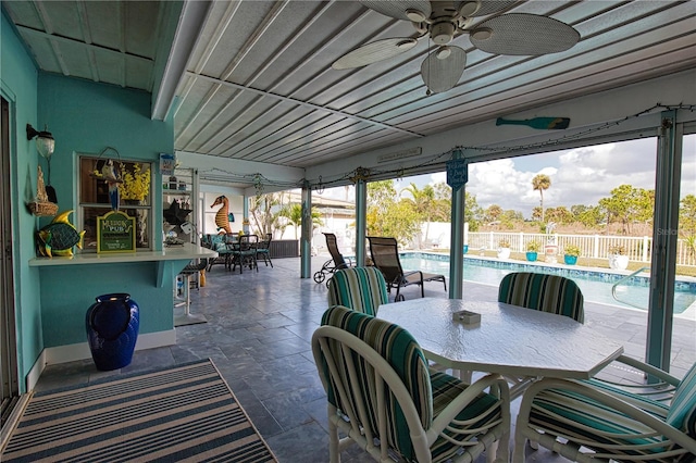 view of patio featuring outdoor dry bar, a fenced in pool, a fenced backyard, outdoor dining space, and a ceiling fan