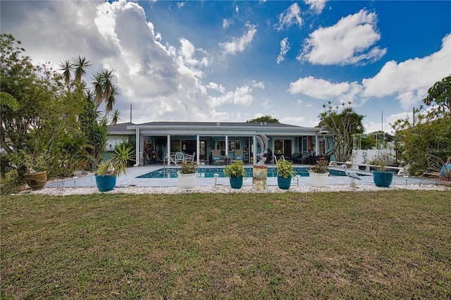 rear view of property featuring a yard, a patio area, and an outdoor pool