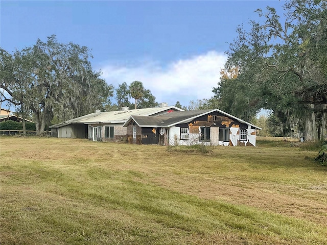 rear view of property featuring a lawn and a chimney