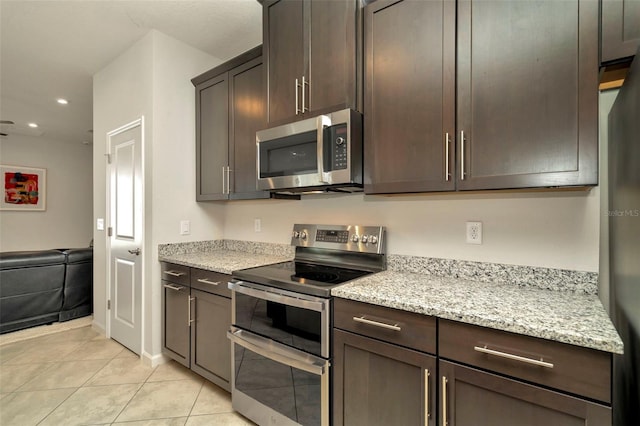 kitchen featuring light tile patterned flooring, dark brown cabinets, stainless steel appliances, and light stone countertops