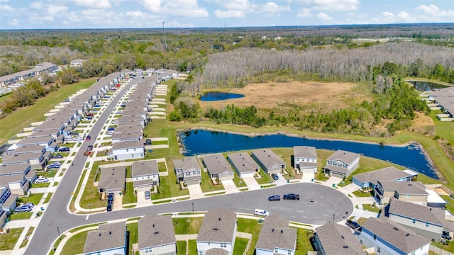 drone / aerial view featuring a view of trees, a water view, and a residential view