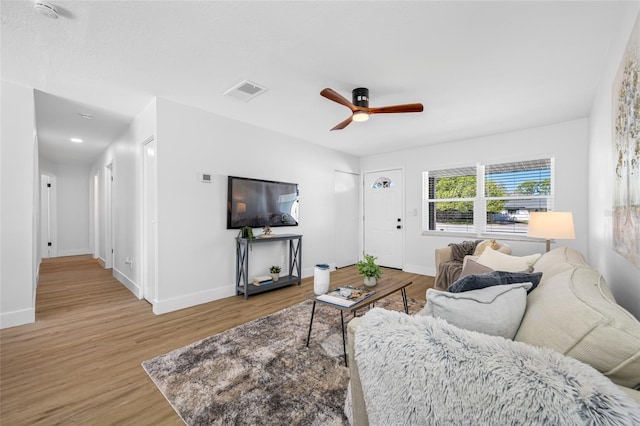 living room featuring light wood-style floors, visible vents, ceiling fan, and baseboards