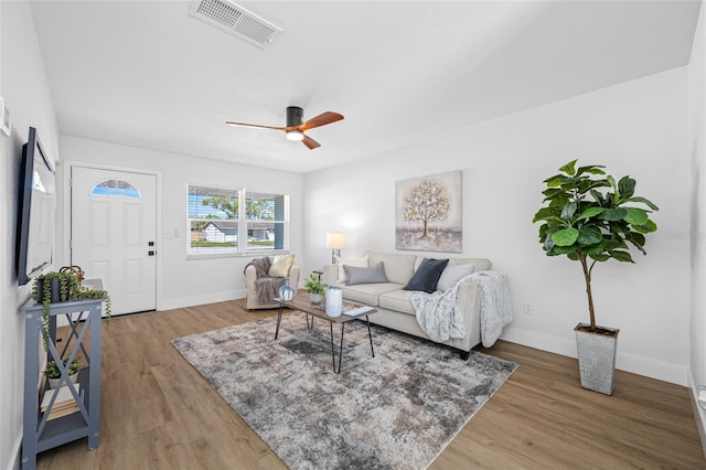 living room with light wood-style floors, visible vents, baseboards, and a ceiling fan