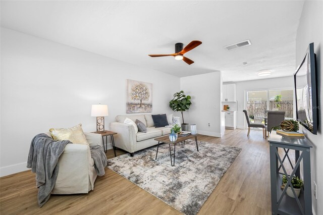 living area with light wood-style flooring, visible vents, ceiling fan, and baseboards