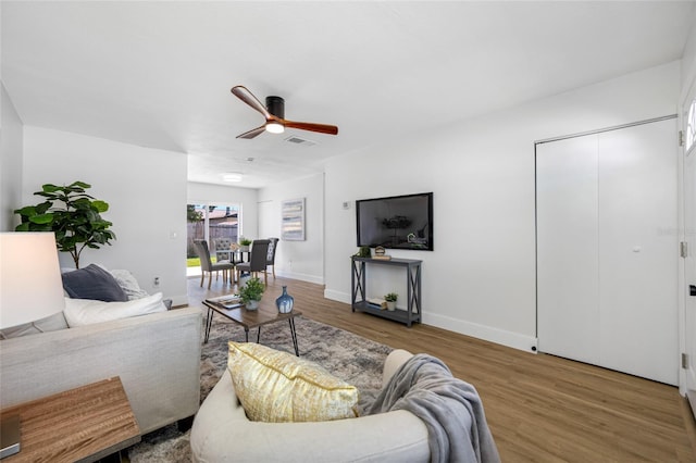 living area with visible vents, ceiling fan, baseboards, and wood finished floors