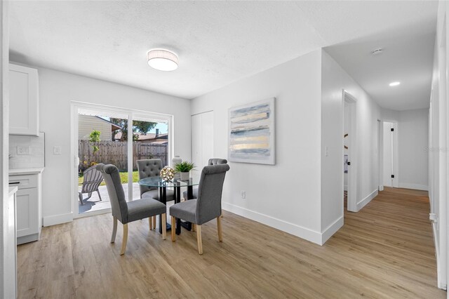 dining space with light wood-type flooring and baseboards