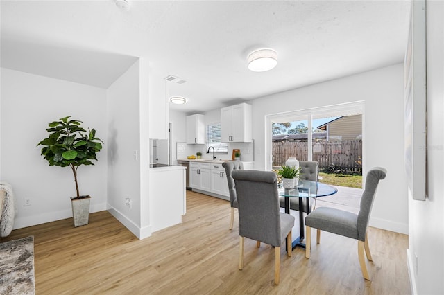 dining space with light wood finished floors, visible vents, and baseboards