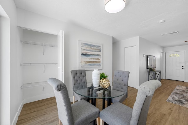 dining area featuring light wood-type flooring, baseboards, and visible vents