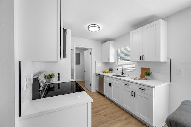 kitchen featuring light wood finished floors, electric range oven, white cabinets, a sink, and dishwasher