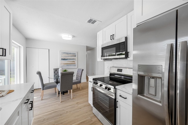 kitchen featuring visible vents, light wood-style flooring, light stone counters, stainless steel appliances, and white cabinetry