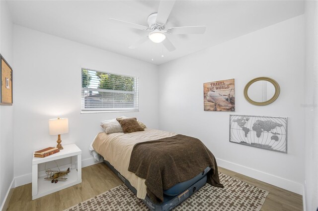 bedroom with a ceiling fan, baseboards, and wood finished floors