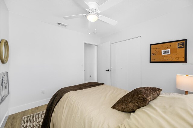 bedroom with a closet, visible vents, ceiling fan, wood finished floors, and baseboards