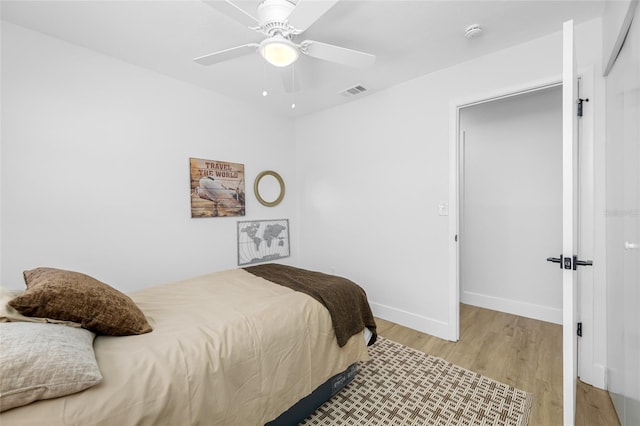 bedroom featuring visible vents, ceiling fan, baseboards, and wood finished floors