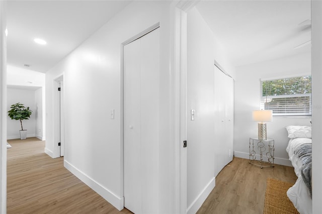 hallway featuring light wood-style flooring, baseboards, and recessed lighting