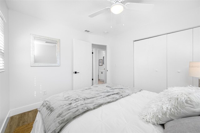 bedroom featuring baseboards, visible vents, a ceiling fan, wood finished floors, and a closet