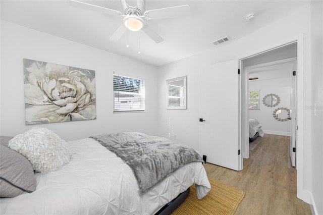 bedroom featuring light wood-style floors, ceiling fan, visible vents, and baseboards