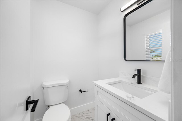 half bath with marble finish floor, toilet, vanity, and baseboards