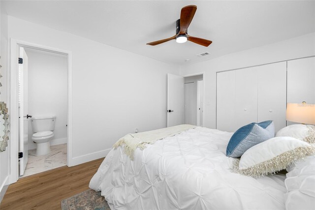 bedroom featuring ensuite bathroom, wood finished floors, visible vents, baseboards, and a closet