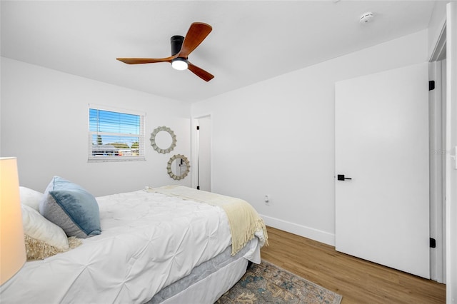 bedroom featuring wood finished floors, a ceiling fan, and baseboards