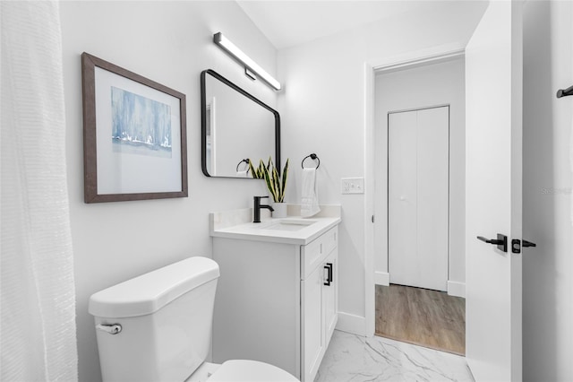 bathroom featuring marble finish floor, baseboards, vanity, and toilet