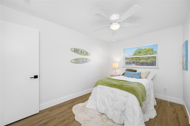 bedroom with a ceiling fan, baseboards, and wood finished floors