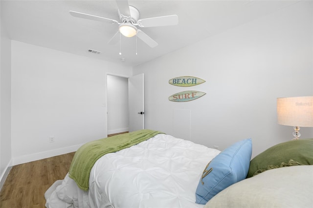 bedroom with ceiling fan, wood finished floors, visible vents, and baseboards