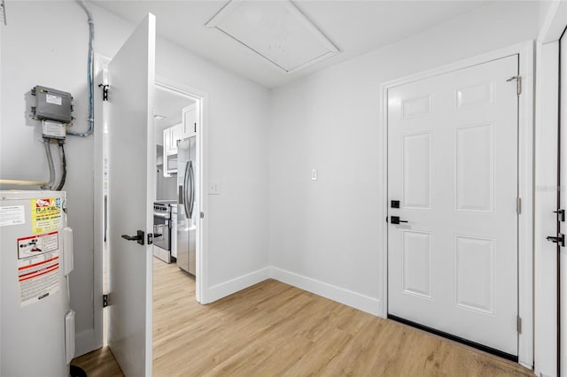 foyer entrance with baseboards, electric water heater, and light wood finished floors