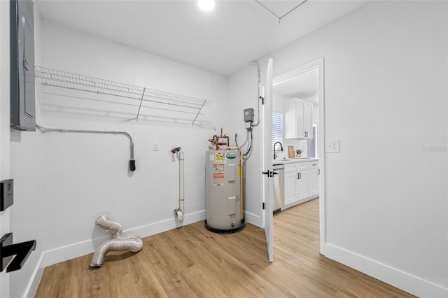 interior space featuring electric water heater, hookup for an electric dryer, light wood-type flooring, laundry area, and baseboards